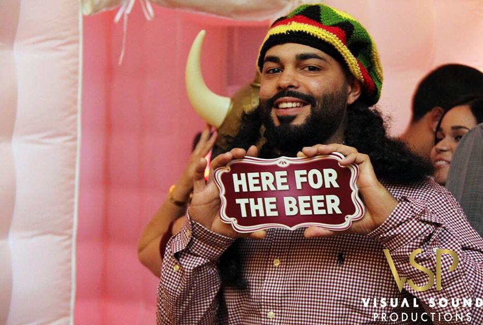 Man holding Here for the Beer sign